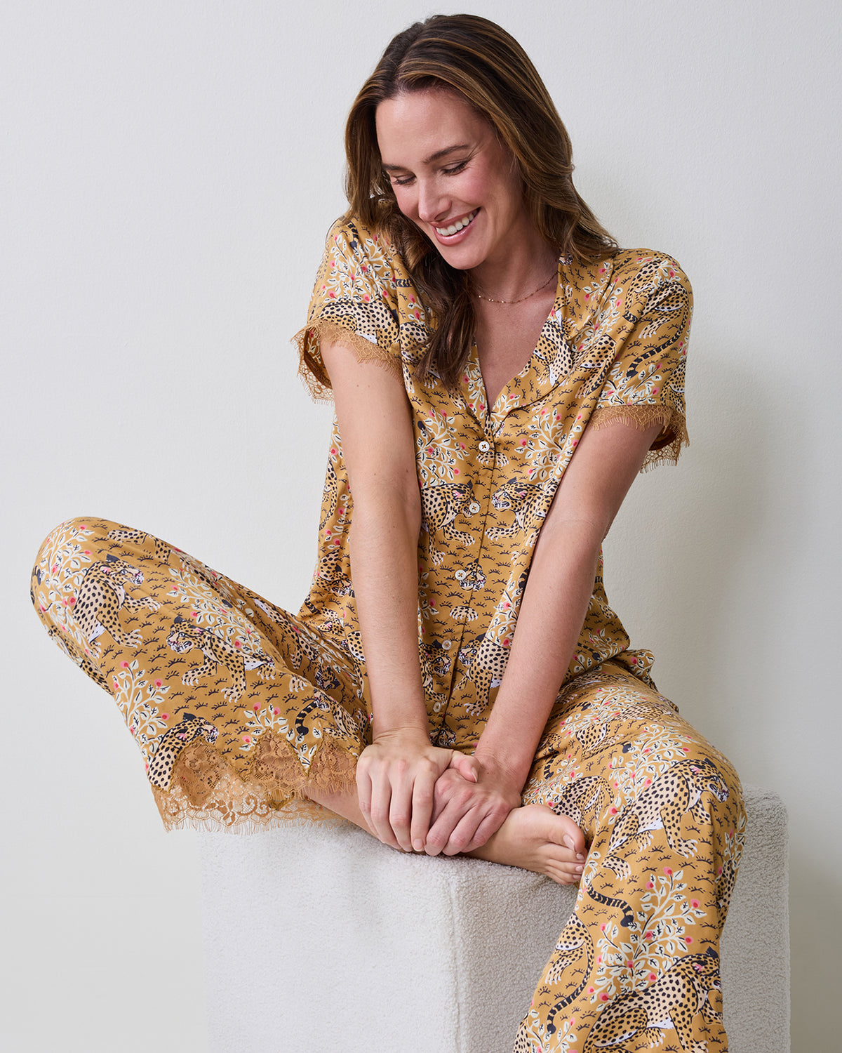 Model seated wearing the Bagheera Tobacco Jackie pajama set with a short-sleeve button-down top and lace-trimmed pants.