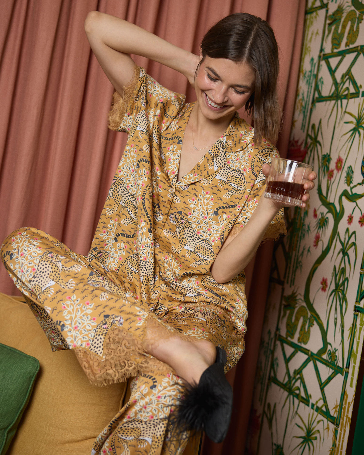 Close lifestyle view of a person wearing the tobacco Bagheera Eco Satin Jackie set, holding a glass while seated.