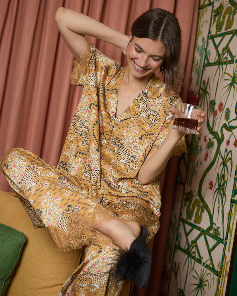 Close lifestyle view of a person wearing the tobacco Bagheera Eco Satin Jackie set, holding a glass while seated.