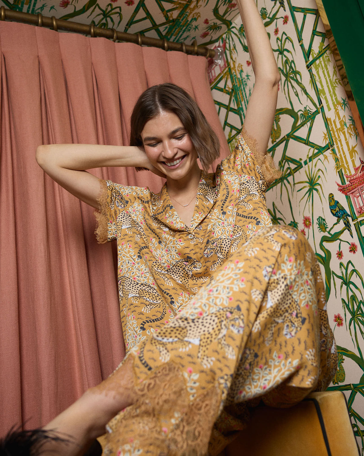 Person wearing the tobacco Bagheera Eco Satin Jackie set, seated with one leg raised and the patterned top and pants visible.