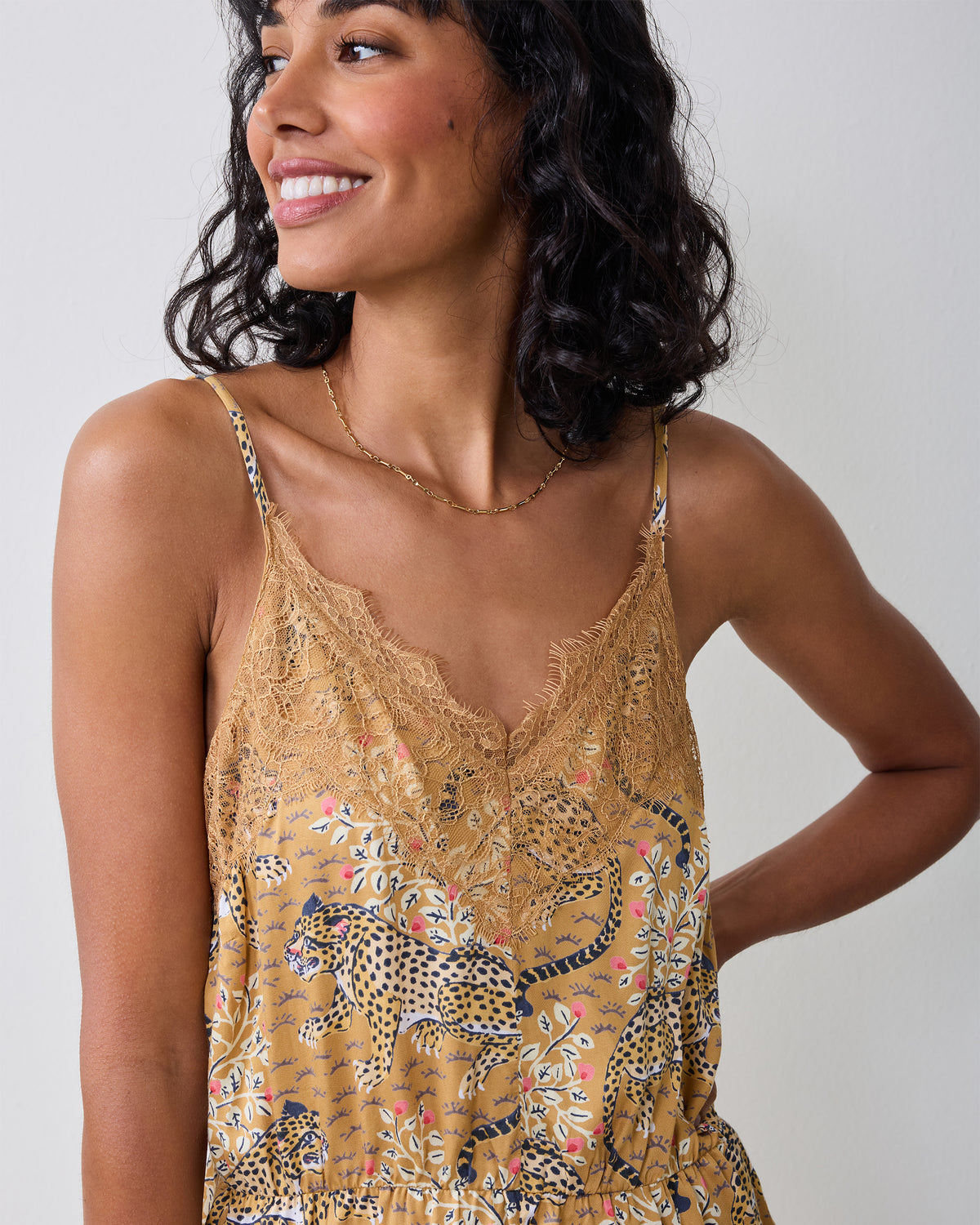 Close-up of the Bagheera tobacco lace romper neckline, showing thin straps and lace edging over the leopard-and-floral print.