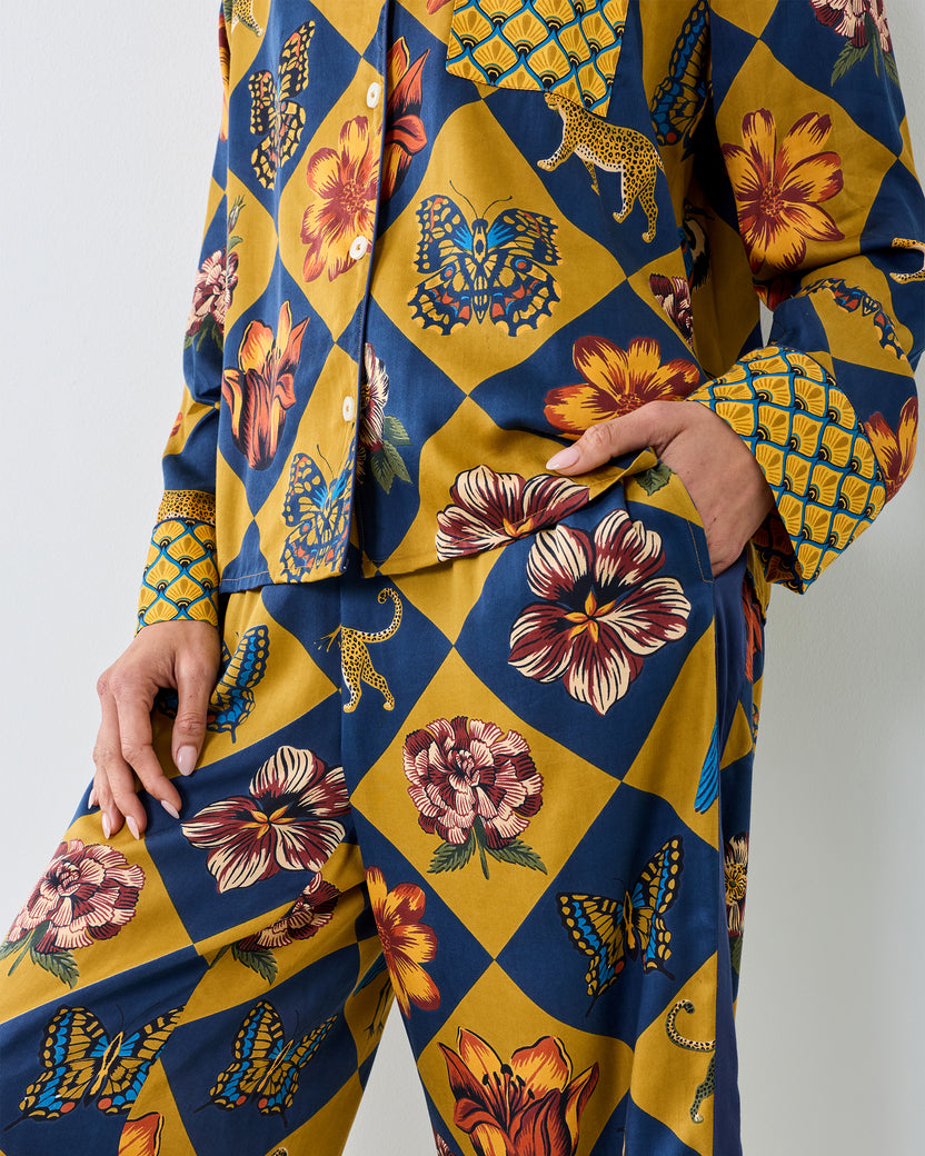 Close-up of the Botanical Checkerboard Rittenhouse pajama set showing the long-sleeve button-front top, pocket, and matching pants with floral, butterfly, and leopard motifs.