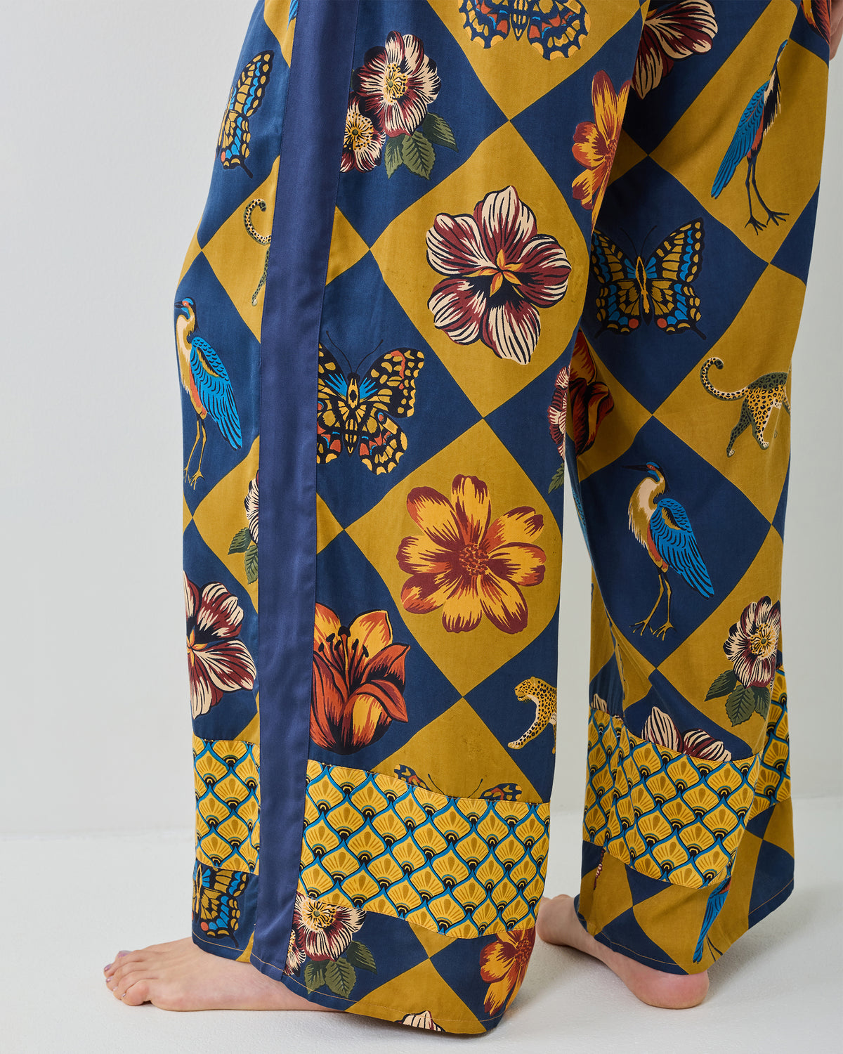 Close-up of the Golden Hour Botanical Checkerboard wide-leg pants showing the floral, butterfly, bird, and animal print.