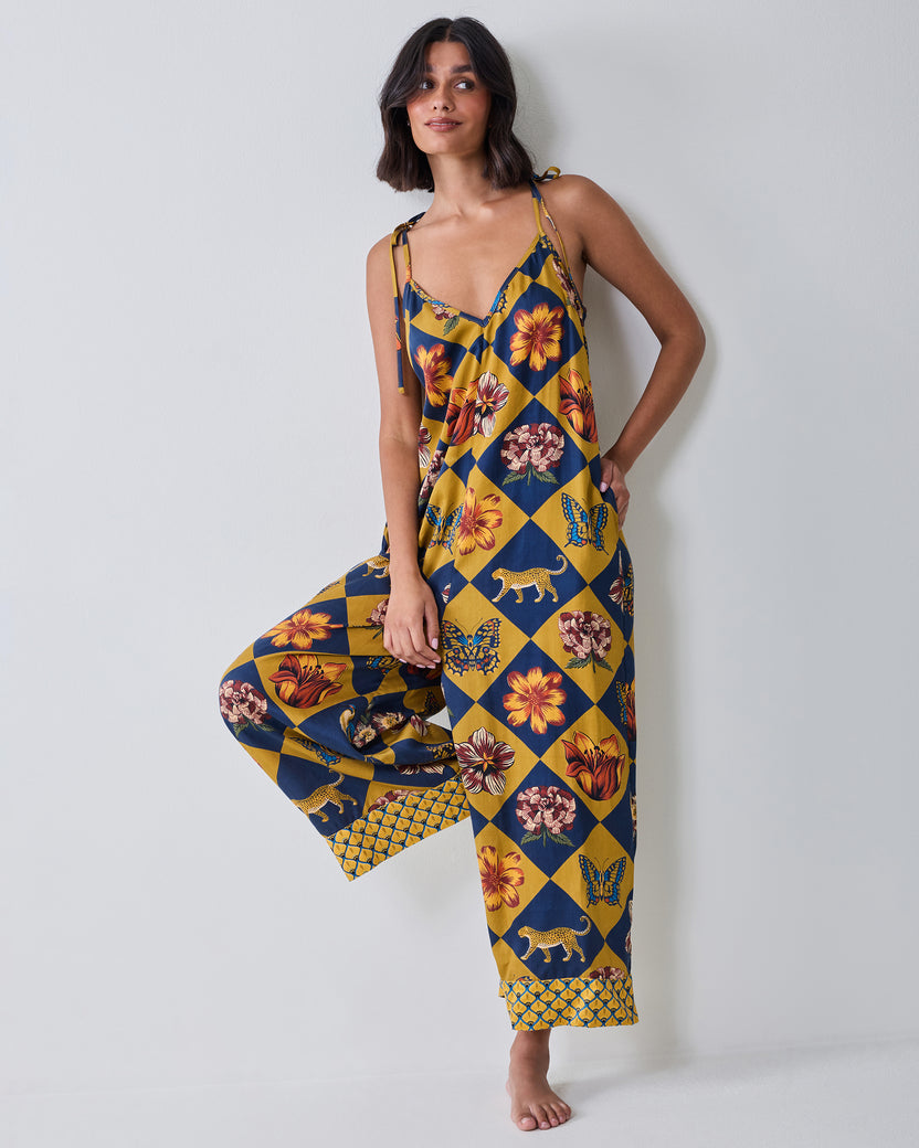 Full front view of the Botanical Checkerboard Jaipur jumpsuit with tie shoulder straps, wide legs, and decorative patterned hems.