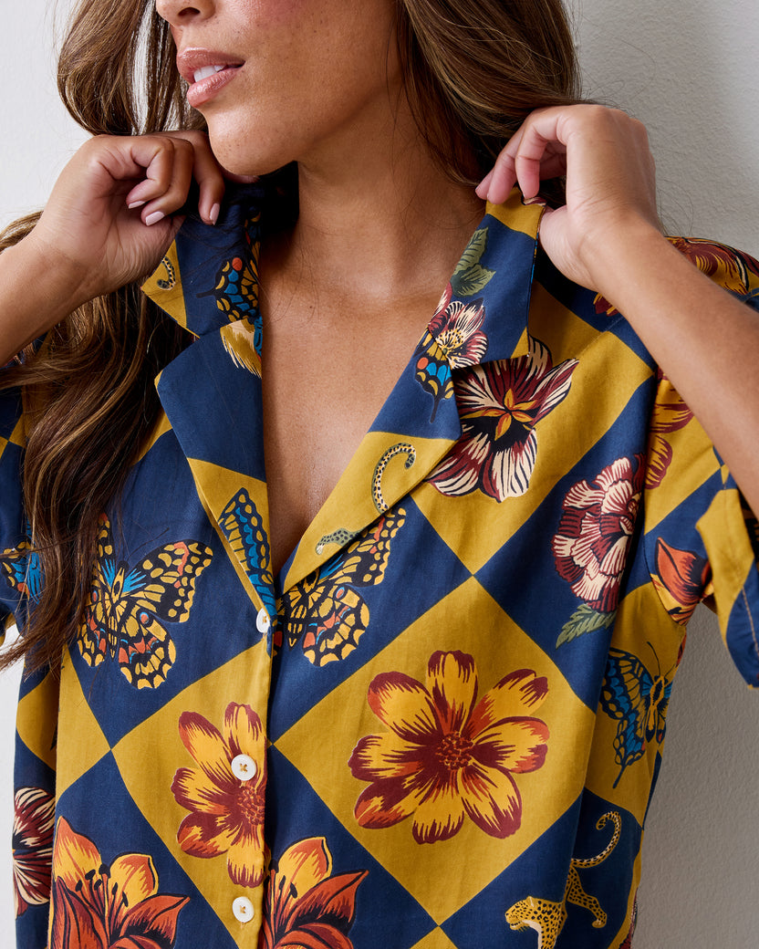 Close-up of the Botanical Checkerboard Sweet Dreams pajama top showing the notched collar, white buttons, and floral, butterfly, and leopard print.