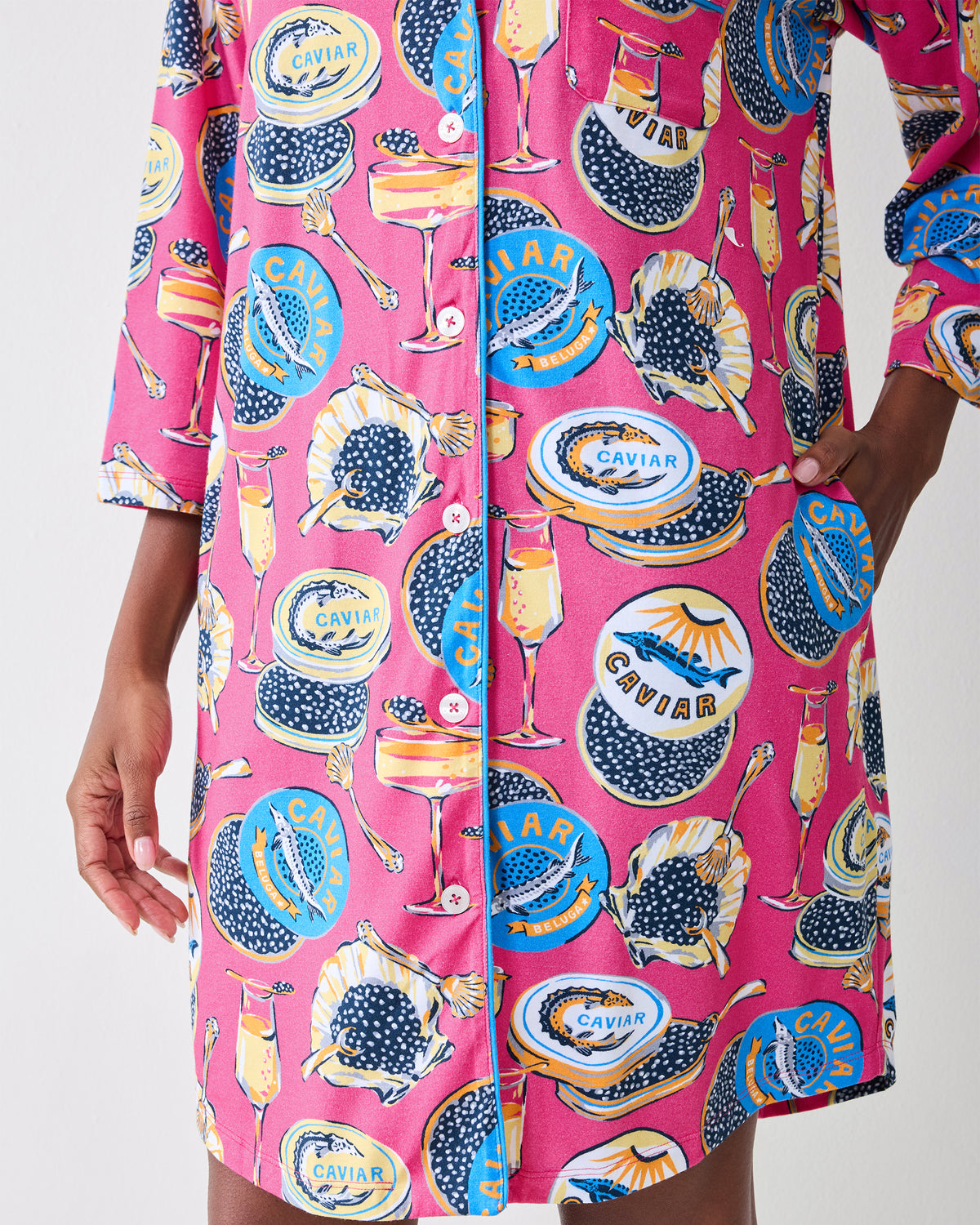 Front view of the hot pink Champagne & Caviar sleep shirt with long sleeves, button front, side pockets, and printed caviar-themed pattern.