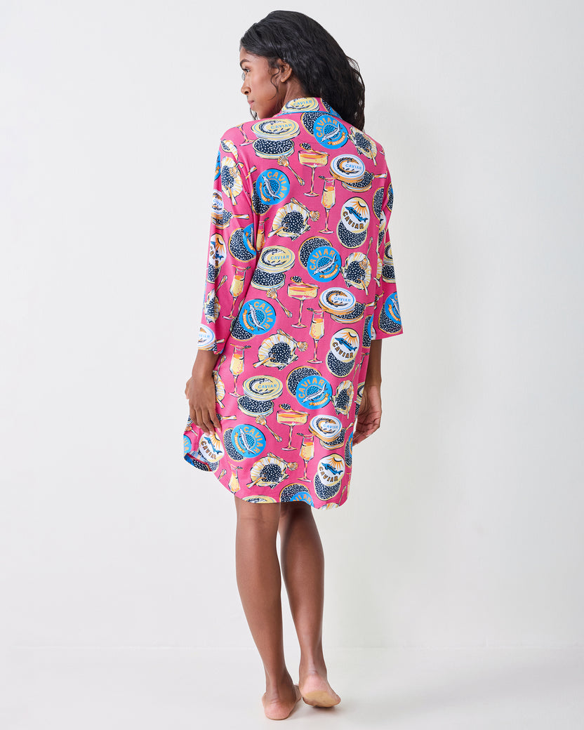 Back view of a hot pink sleep shirt with a champagne and caviar-themed print.