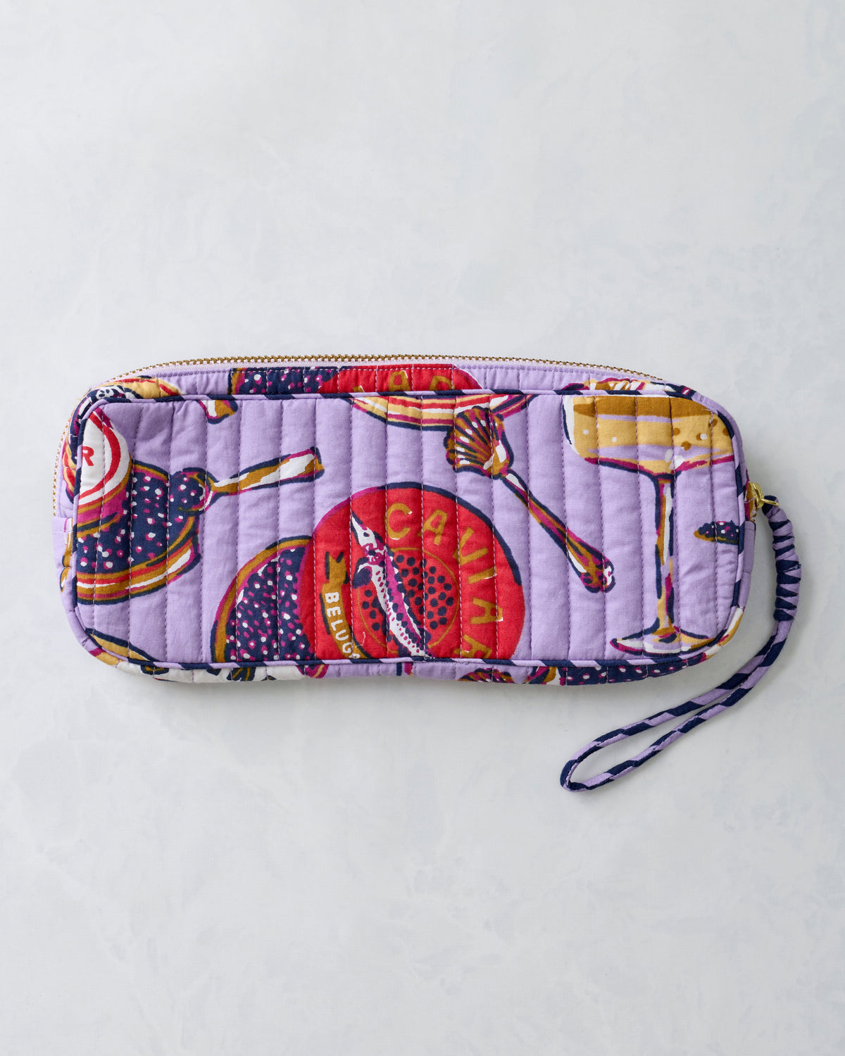 Lavender quilted zippered sunglasses case shown from the reverse side with a wrist strap and printed food-themed motifs.