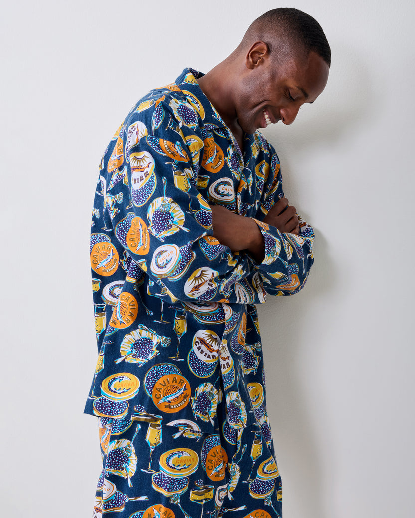 Side view of a model wearing the navy Champagne & Caviar long pajama set with a printed caviar-themed design.