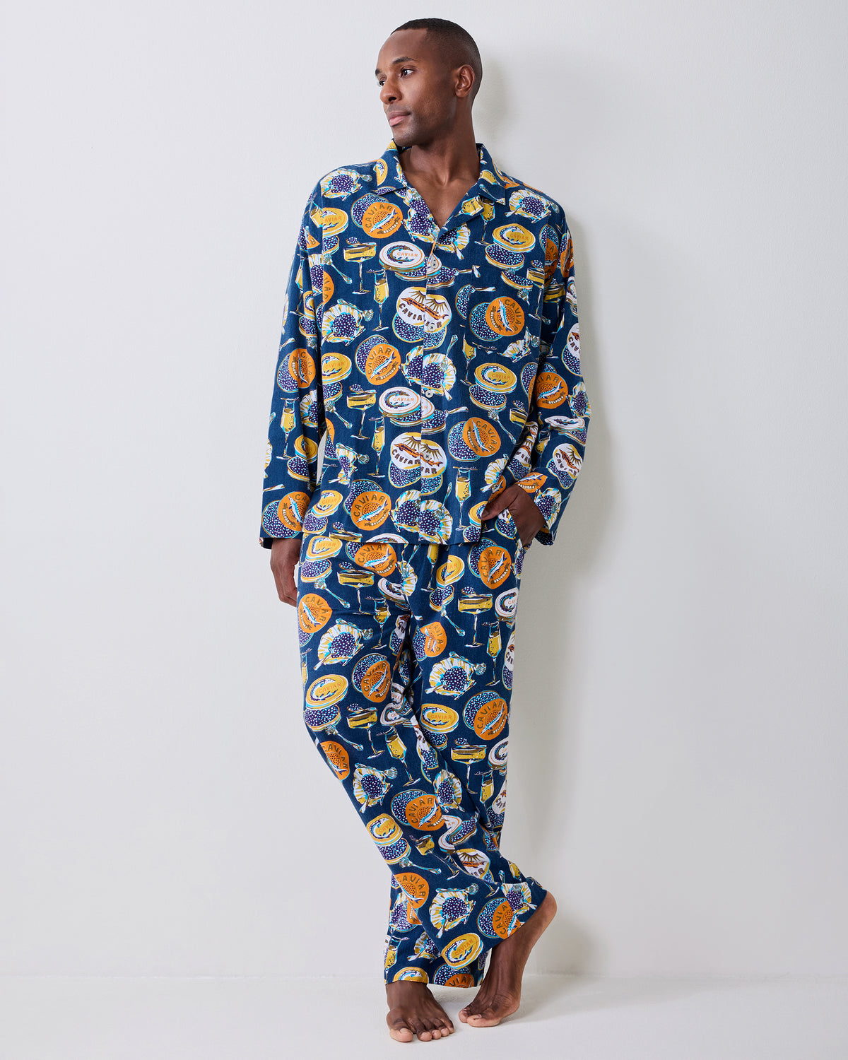 Front view of a model wearing the navy Champagne & Caviar long pajama set with a caviar-themed print.