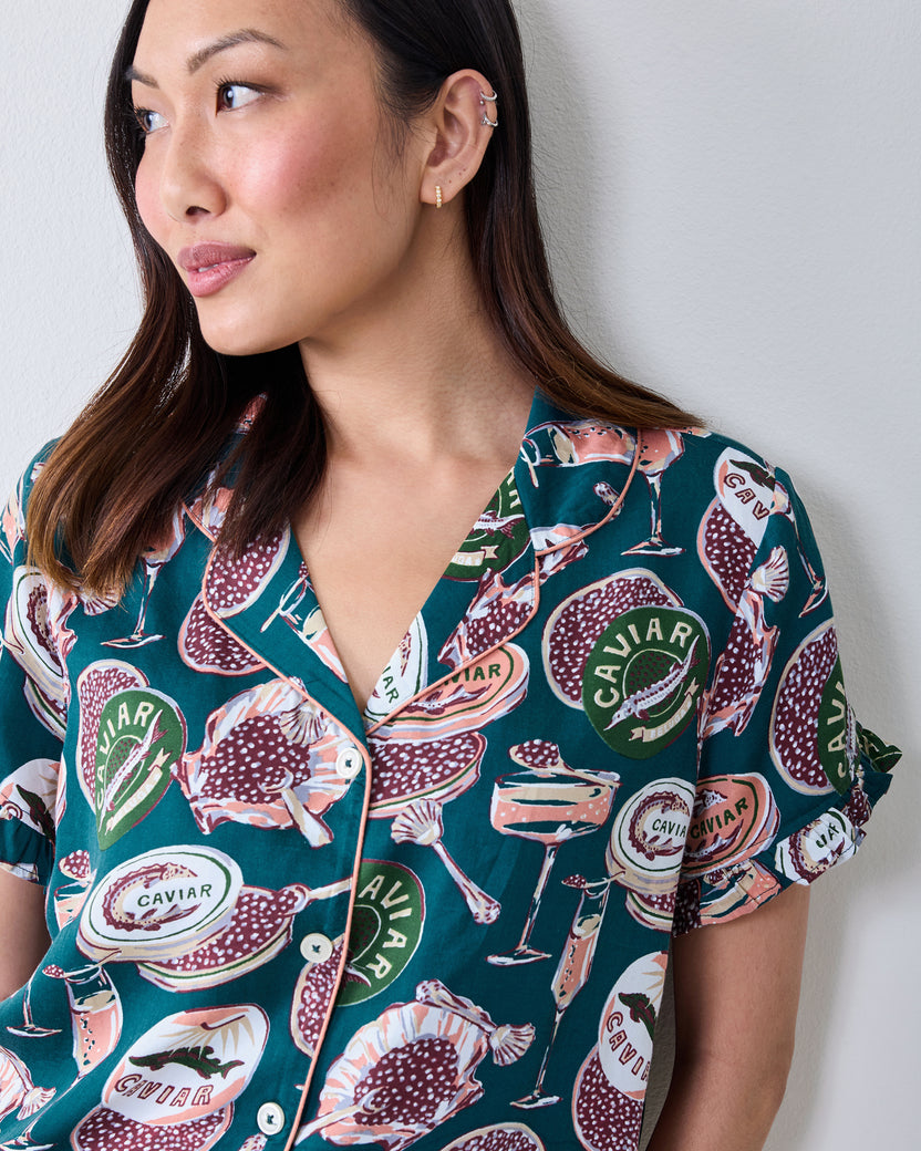 Close view of the short-sleeve satin pajama top with ruffled sleeves and a caviar-themed print.