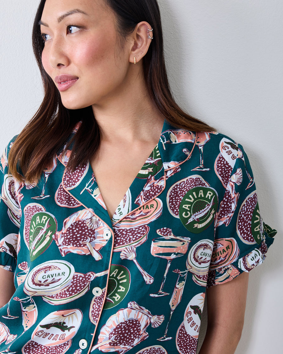 Close view of the short-sleeve satin pajama top with ruffled sleeves and a caviar-themed print.