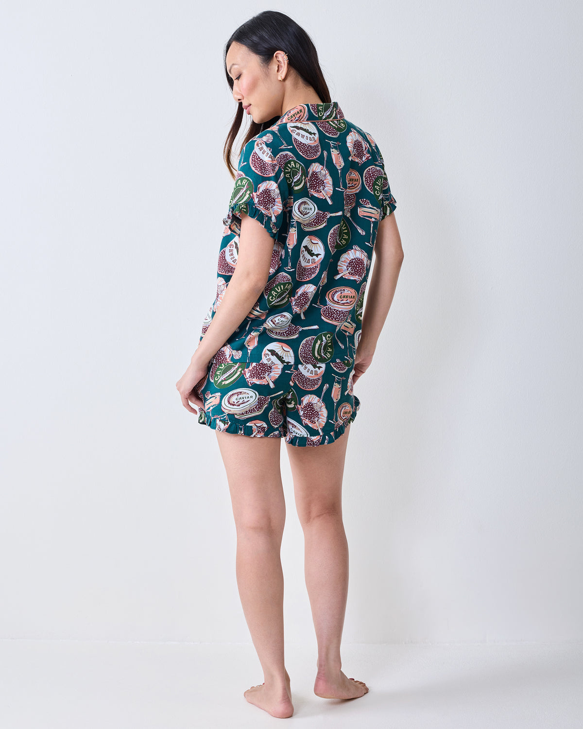 Back view of a short satin pajama set with a caviar-themed print and ruffled short hem.