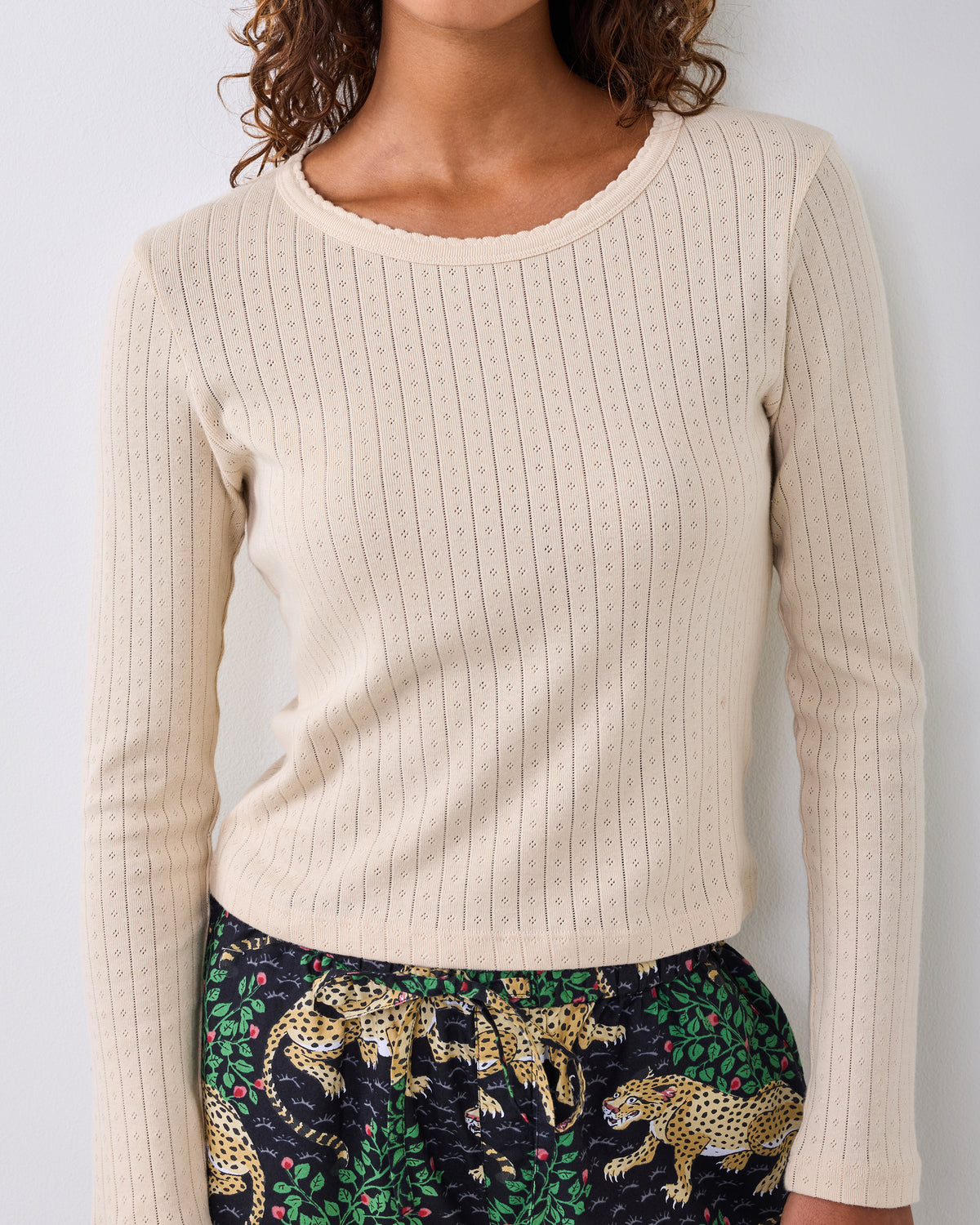 Front view of a cool ecru long-sleeve pointelle top with a scalloped neckline and vertical eyelet pattern.