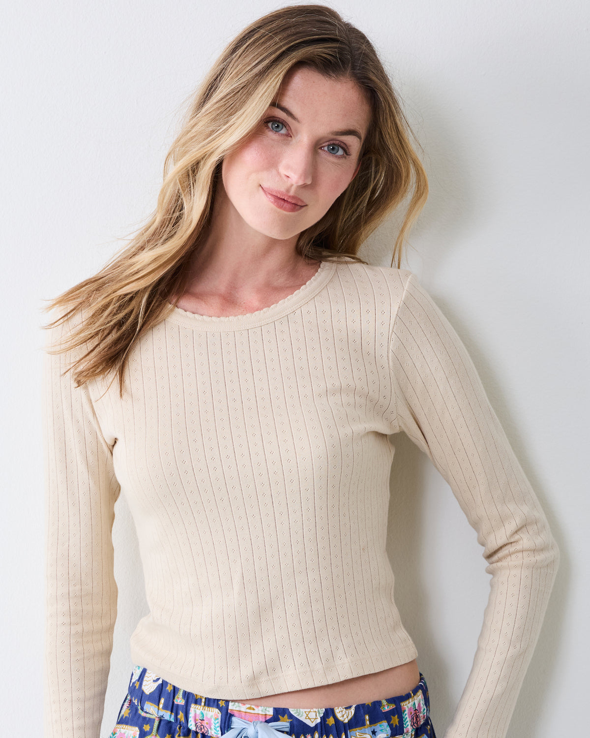 Close front view highlighting the cool ecru pointelle texture and scalloped neckline of the long-sleeve top.