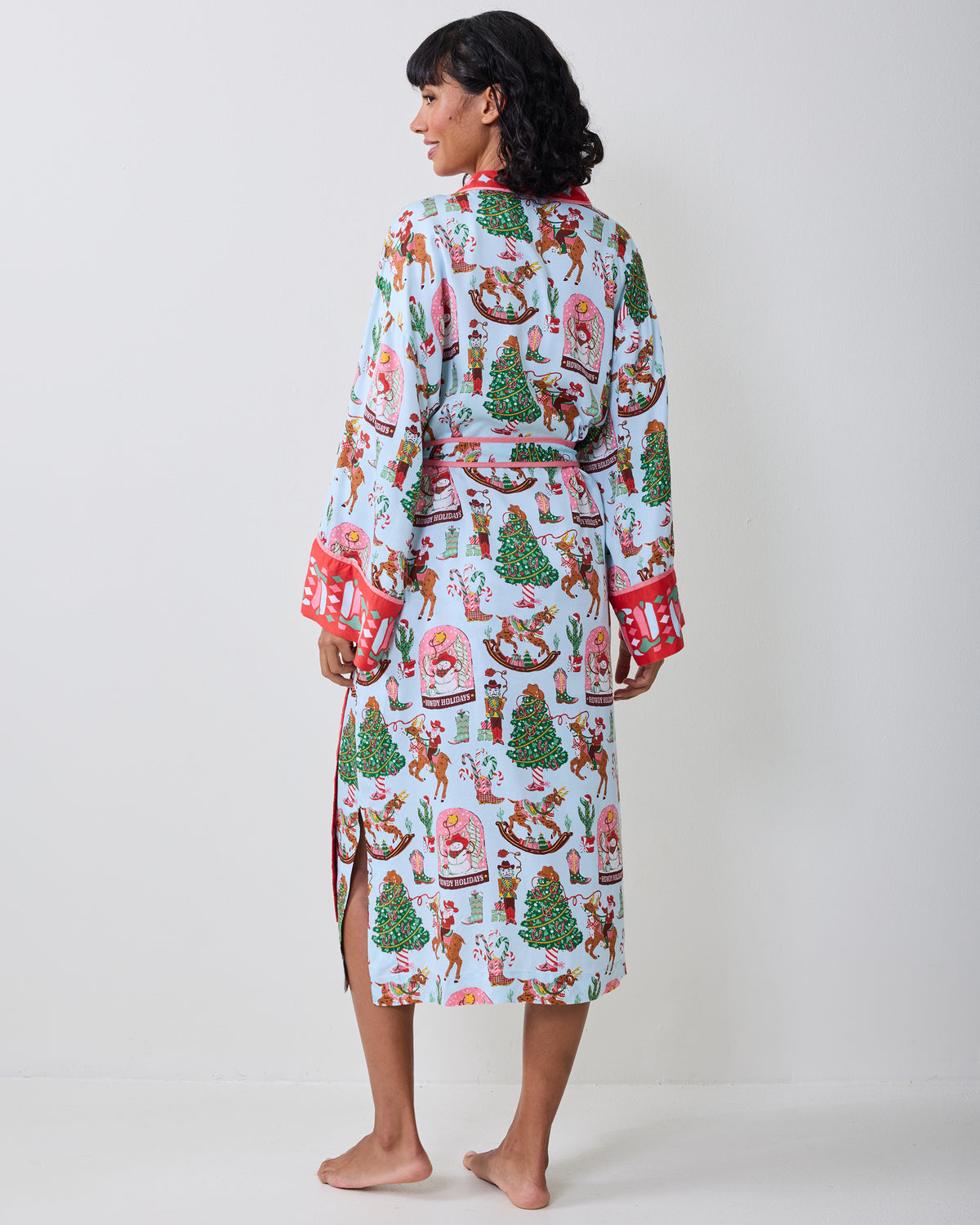 Back view of the pale blue Cowboy Christmas robe showing the holiday print, waist tie, red cuff trim, and side slit.