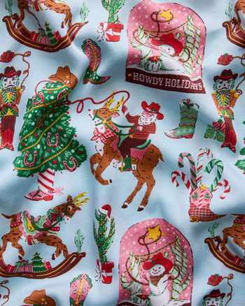Seamless light-blue Cowboy Christmas pajama print with Santa, reindeer, cowboy boots, Christmas trees, candy canes, and a panel reading “HOWDY HOLIDAYS.”