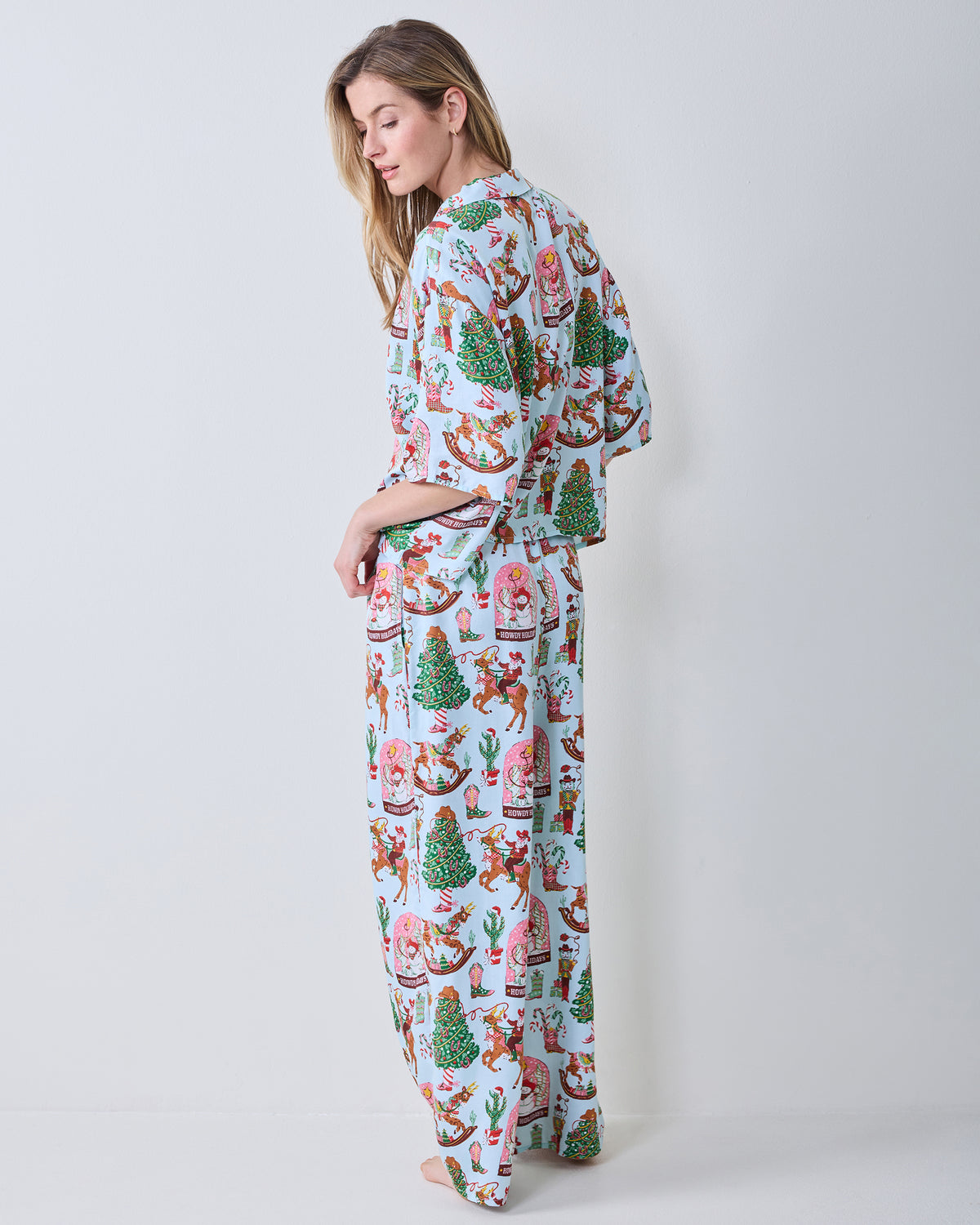 Side view of the short-sleeve button-down top and matching wide-leg pants in the Cowboy Christmas print.