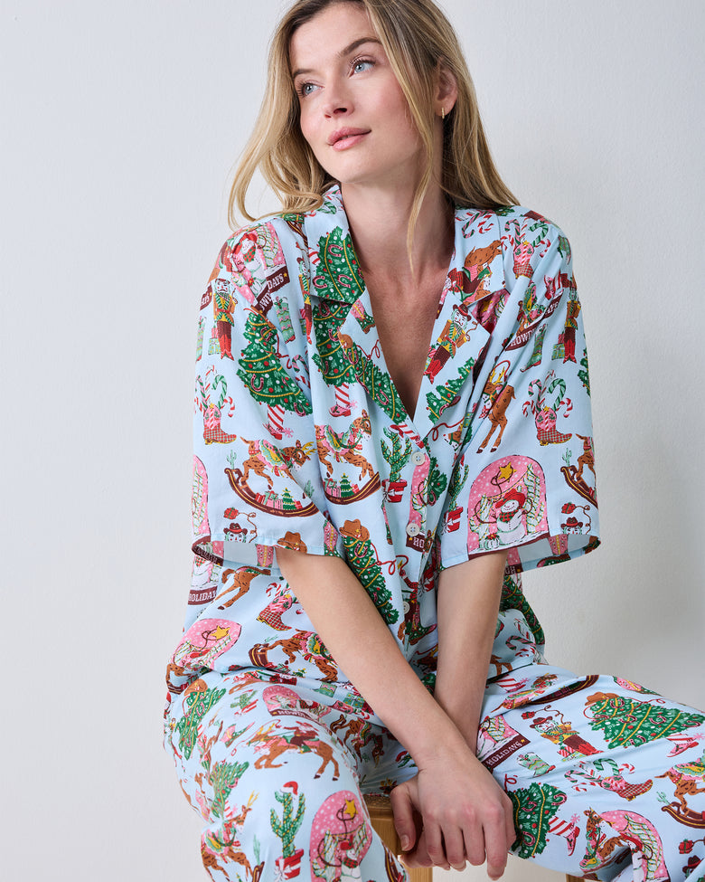 Close-up of the short-sleeve button-down top and printed wide-leg pants in the Cowboy Christmas set.