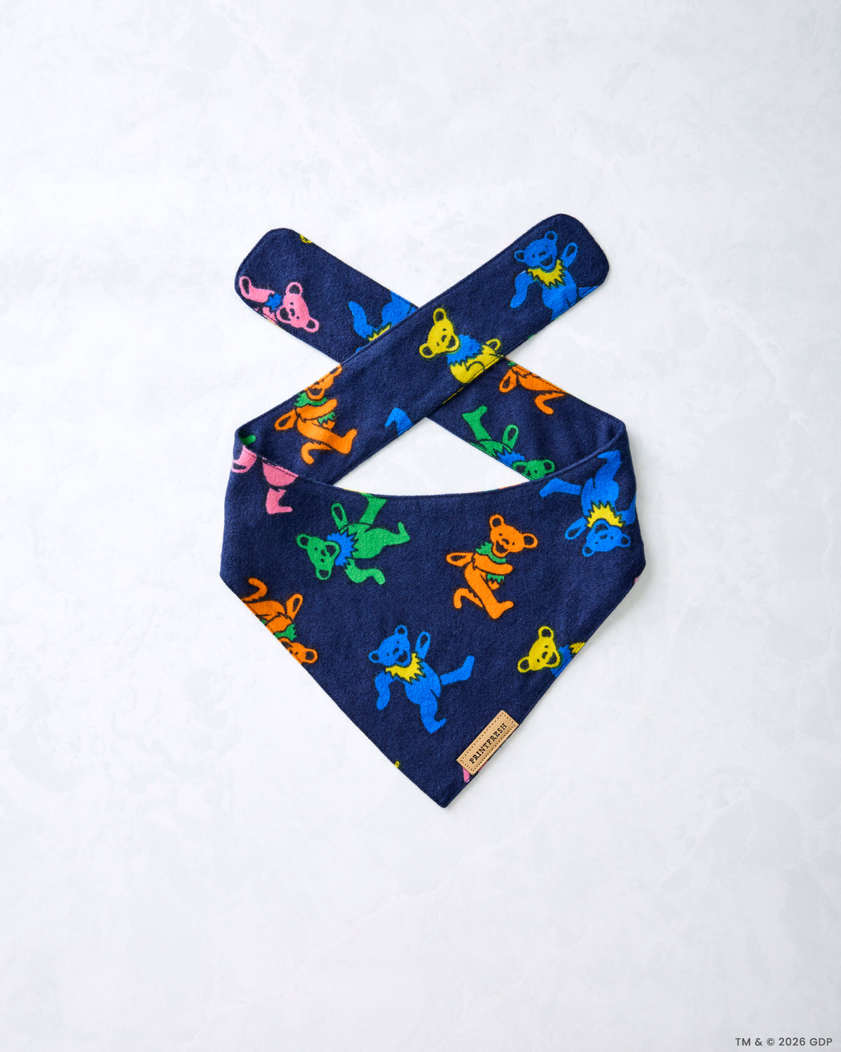 Navy Dancing Bears pet bandana laid flat at an angle, showing crossed tie straps and colorful bear figures.