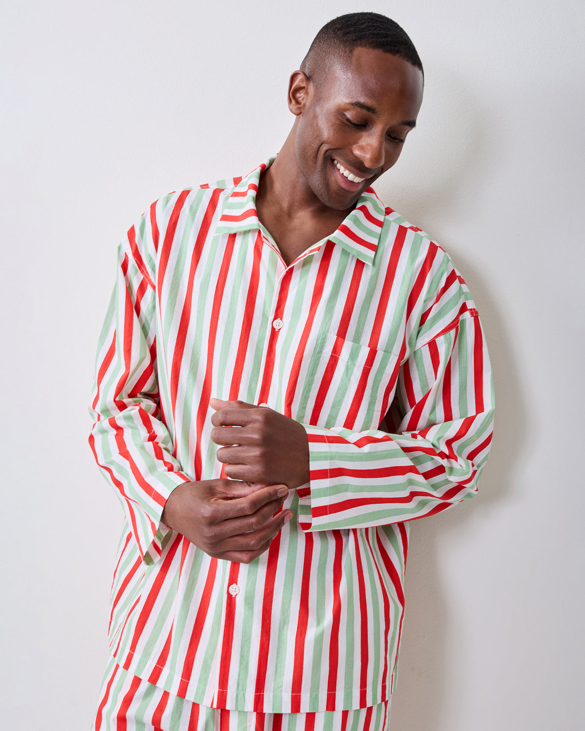 Person wearing the Elf Stripes men's long pajama set with vertical sage and cherry stripes, shown from the front.