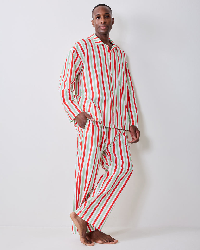 Angled full-length view of a person wearing the Elf Stripes sage and cherry long pajama set with one hand in a pocket.