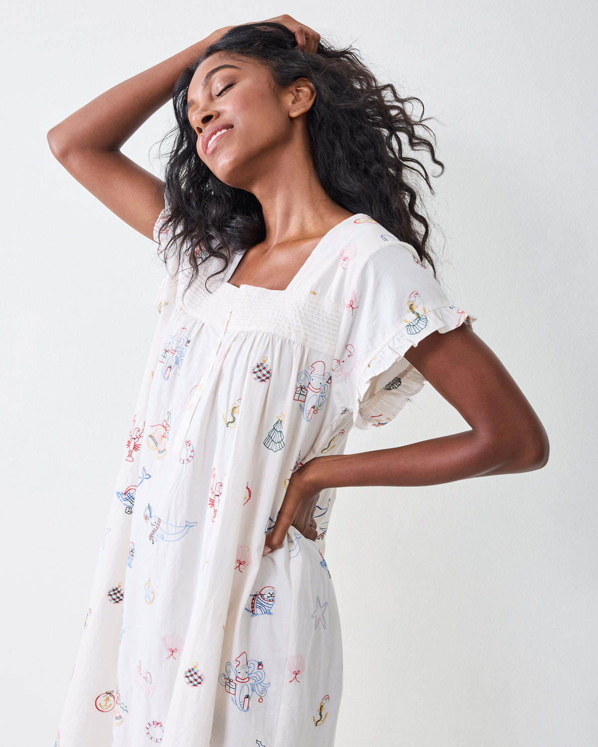 Three-quarter side view of the Embroidered Yule Tides daylight nightgown showing its loose silhouette, ruffled sleeves, and embroidered motifs.