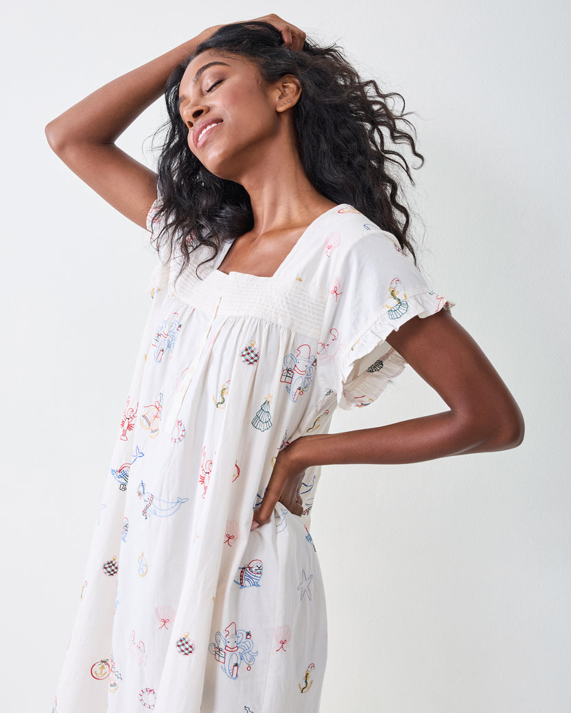 Three-quarter side view of the Embroidered Yule Tides daylight nightgown showing its loose silhouette, ruffled sleeves, and embroidered motifs.