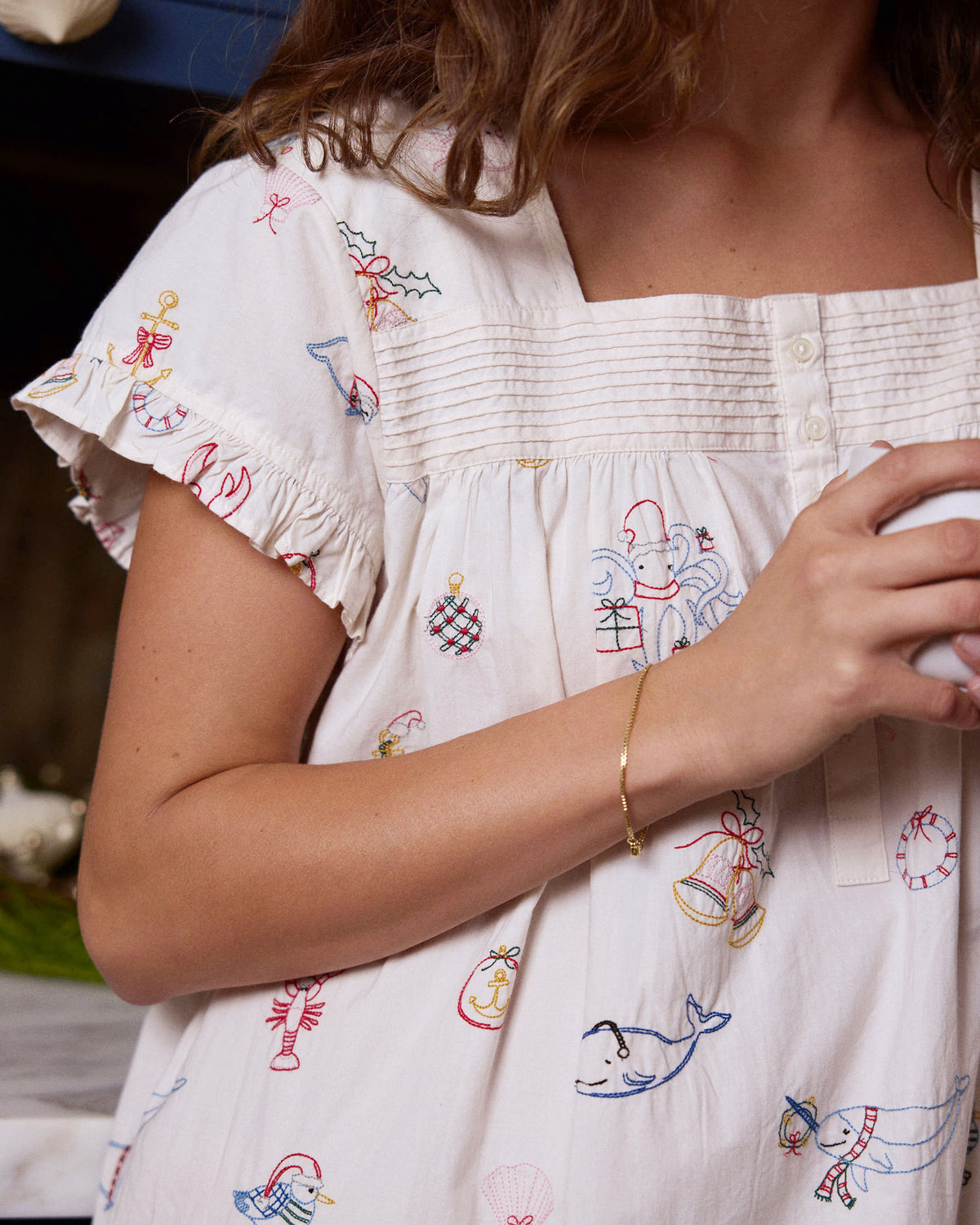 Close-up of the Embroidered Yule Tides daylight nightgown showing the pintuck neckline, buttons, ruffled sleeve, and embroidered motifs.