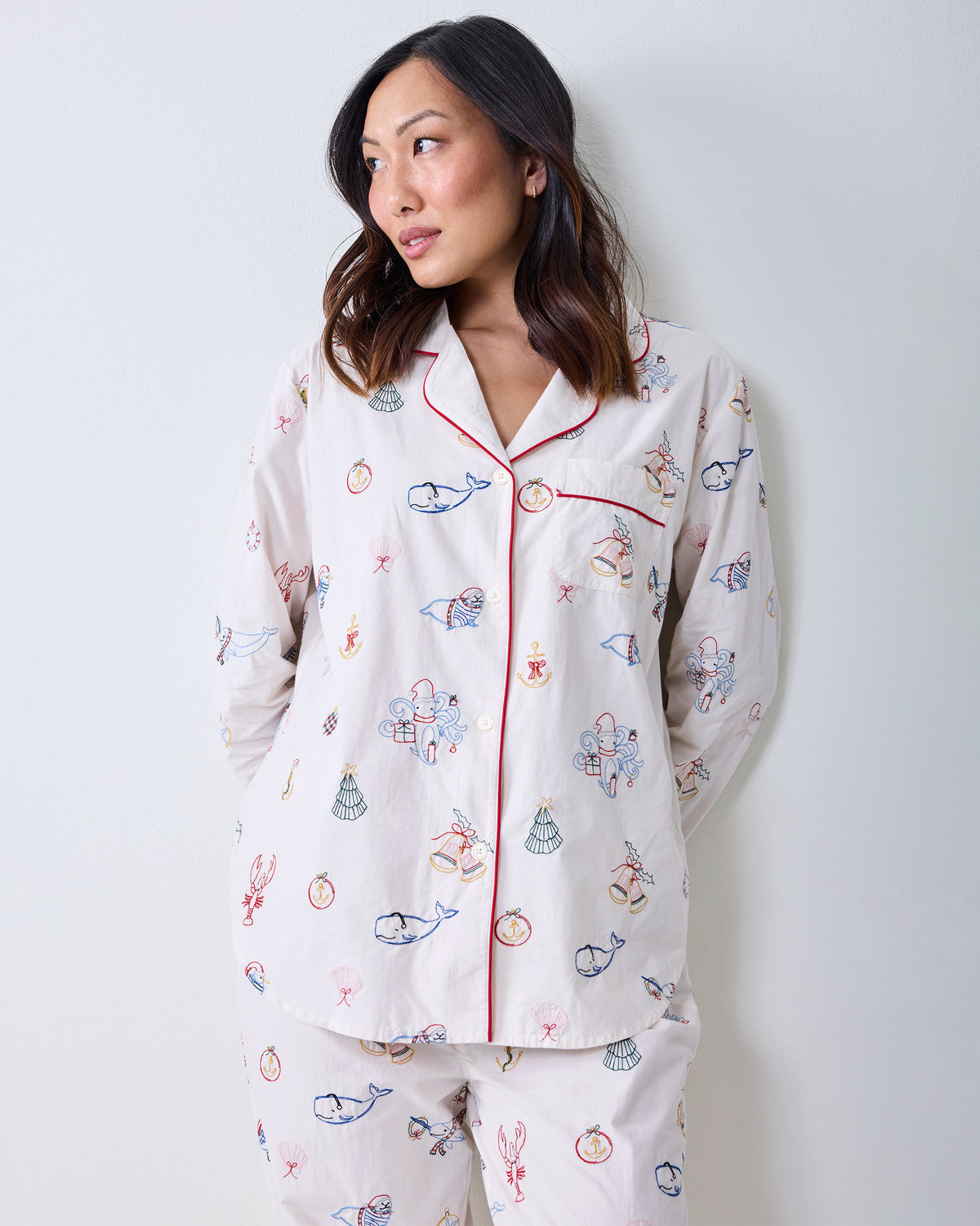 Full-length view of the Cloud long pajama set with a white button-front shirt and matching full-length pants covered in embroidered nautical and holiday motifs.