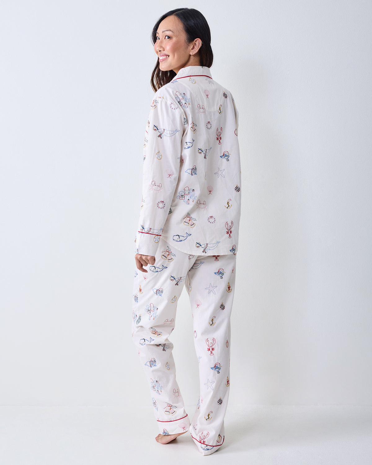 Back view of a person wearing the Embroidered Yule Tides long-sleeve pajama top and matching pants with embroidered nautical motifs.