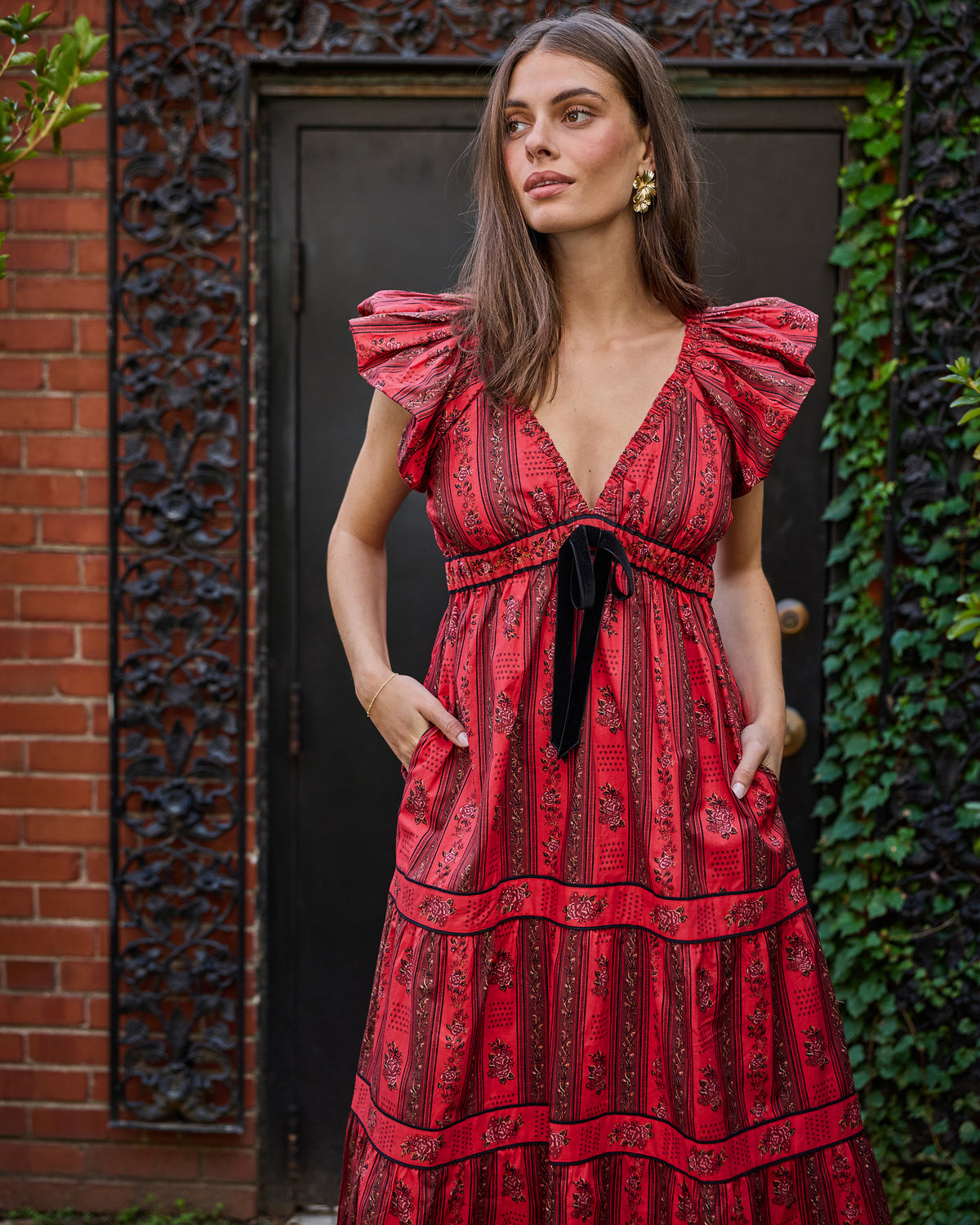 Full front view of the heirloom red Festive Roses Cecily Dress with ruffled sleeves, waist tie, side pockets, and tiered skirt.