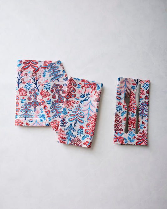 Folded printed dinner napkins displayed with a fork and knife tucked into one napkin.