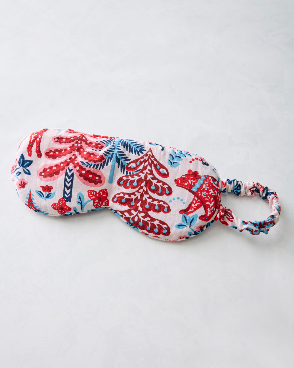 Cream eye mask with red and blue woodland-pattern print and an elastic strap.