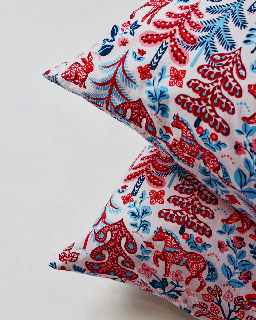 Close-up of overlapping pillowcase corners showing the red, navy, and pink forest print.