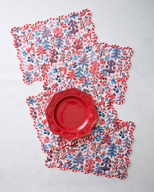 Four Folklore Forest placemats arranged with a red plate placed on top of them.