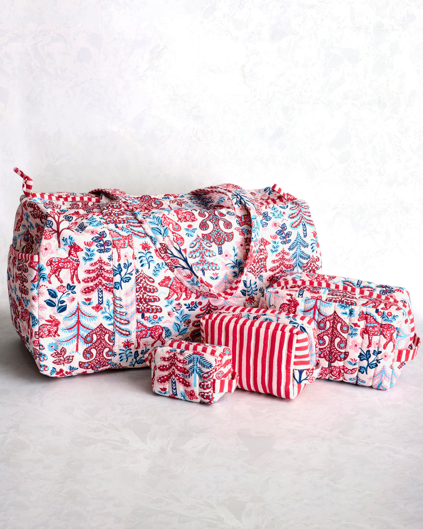 Quilted duffle bag and three matching pouches in a red, blue, and cream forest print, shown together.