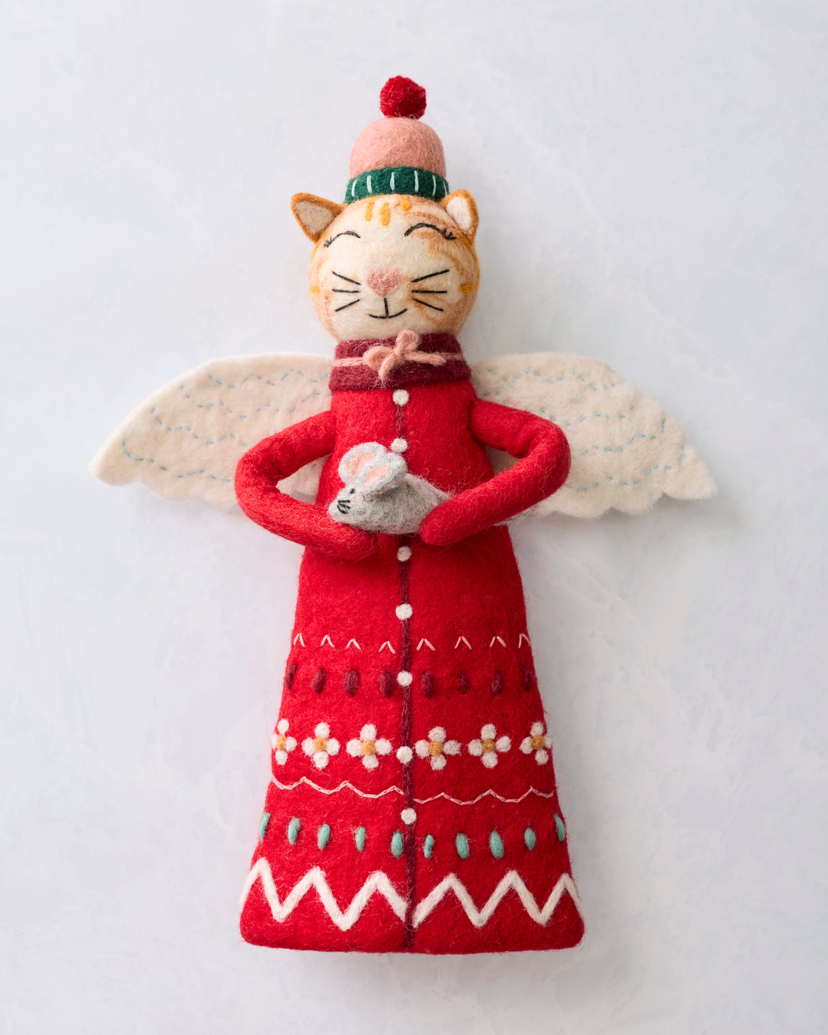 Front view of a red cat tree topper with white wings, a winter hat, and a small mouse held in its paws.