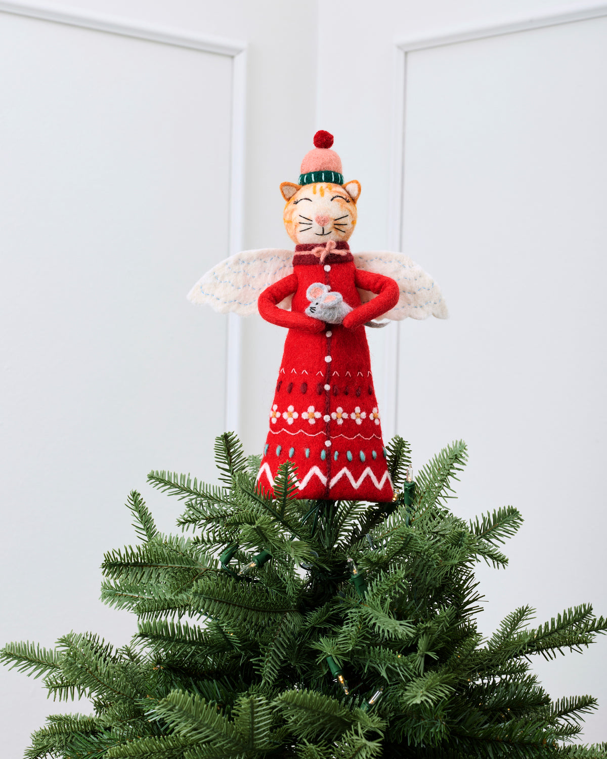 Red cat tree topper with white wings displayed on top of a decorated Christmas tree.