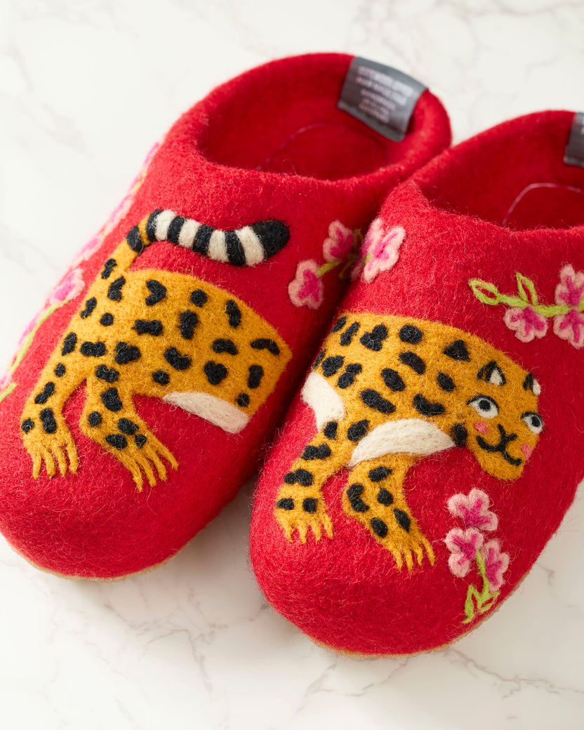 Close-up of red slippers showing yellow spotted leopard embroidery, striped tails, and pink flowers.