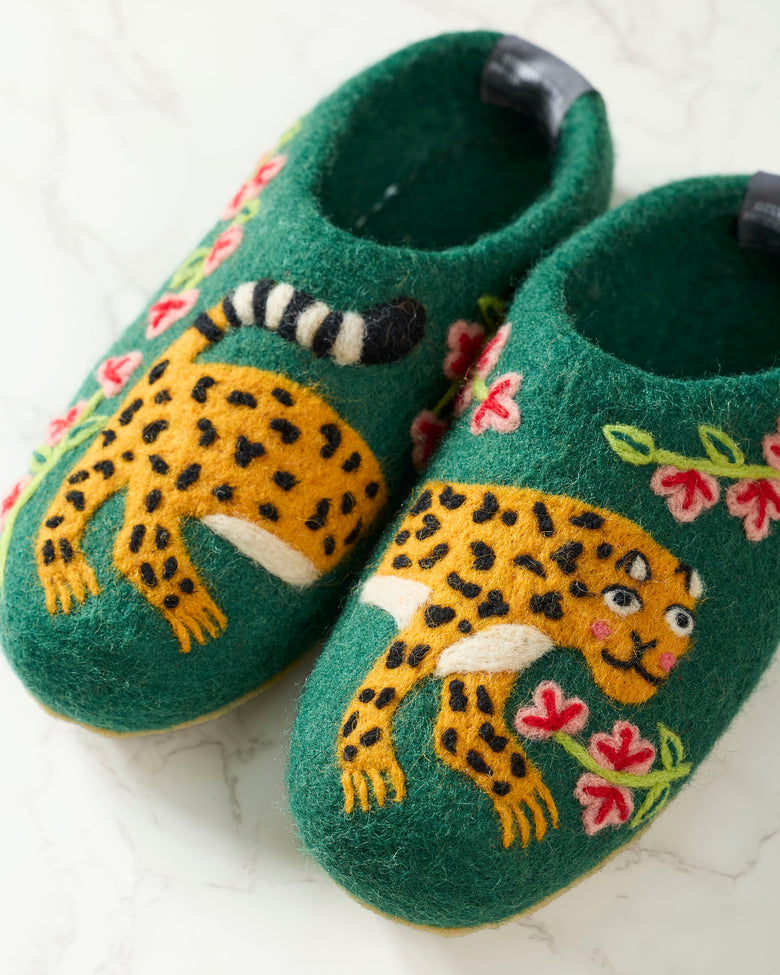 Close-up of green slippers showing yellow spotted leopard embroidery, striped tails, and pink flowers.