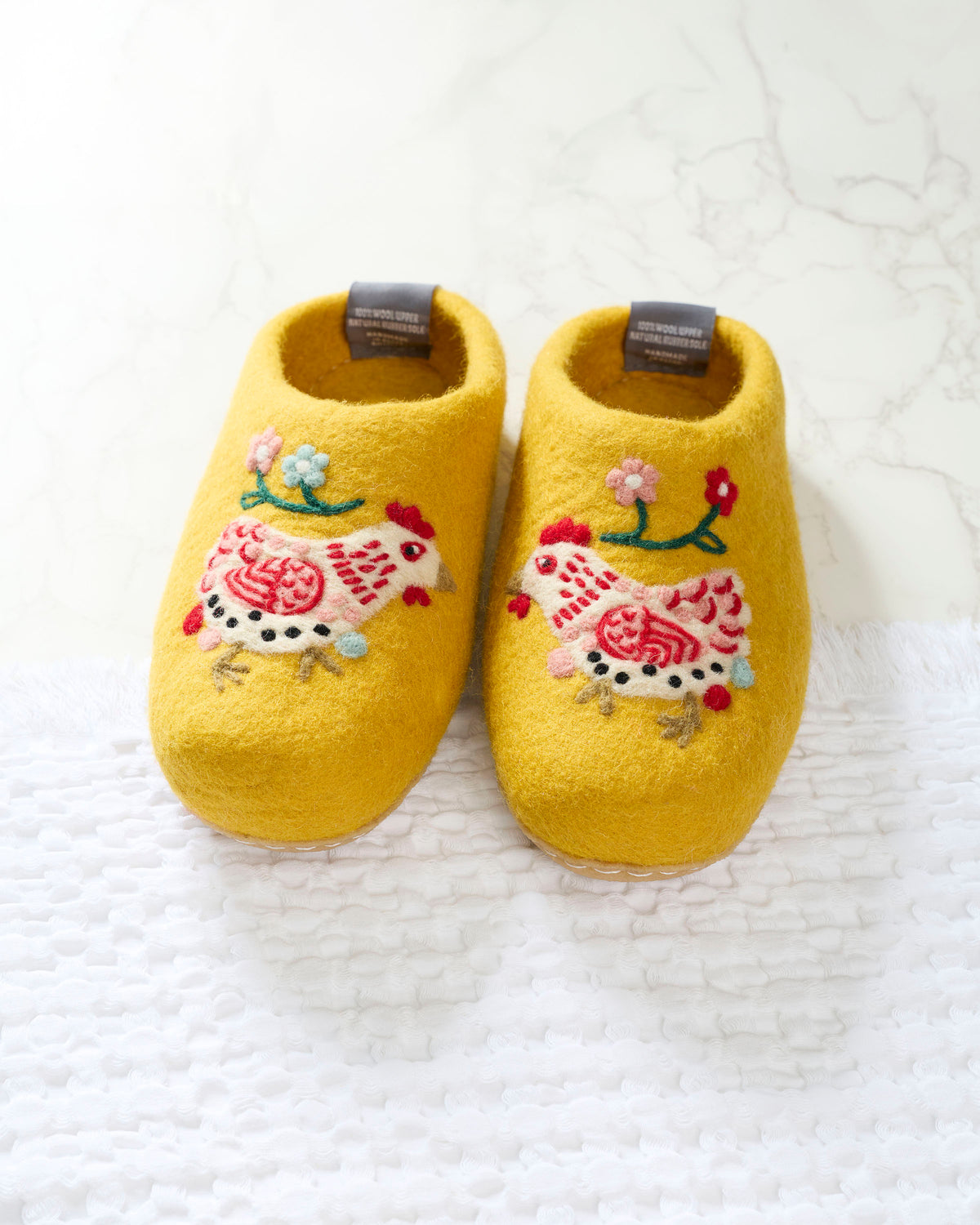 Pair of yellow slippers with embroidered white-and-red hens and small pastel flowers.
