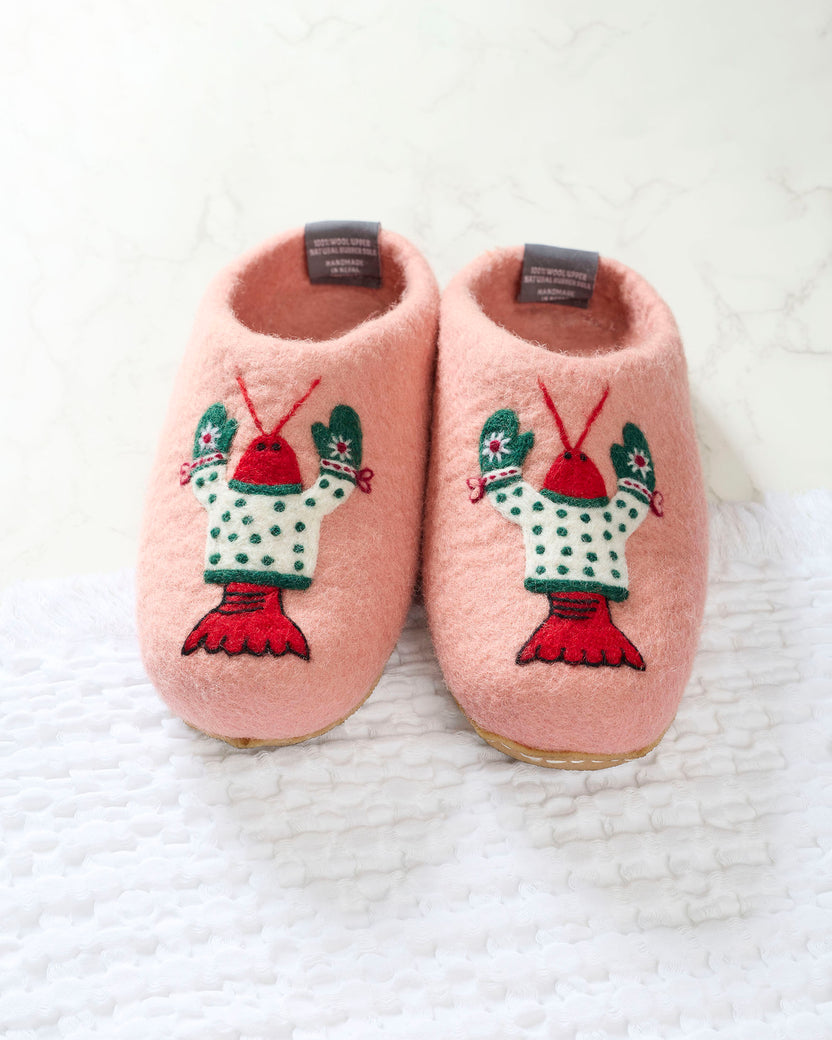 Front view of pink felt slippers with embroidered lobster characters wearing white sweaters and green mittens.
