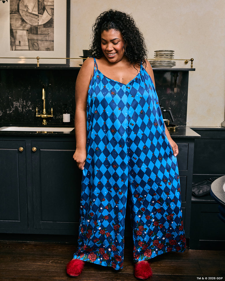 Person wearing the blue argyle-print Jaipur jumpsuit with rose and star motifs in a kitchen.
