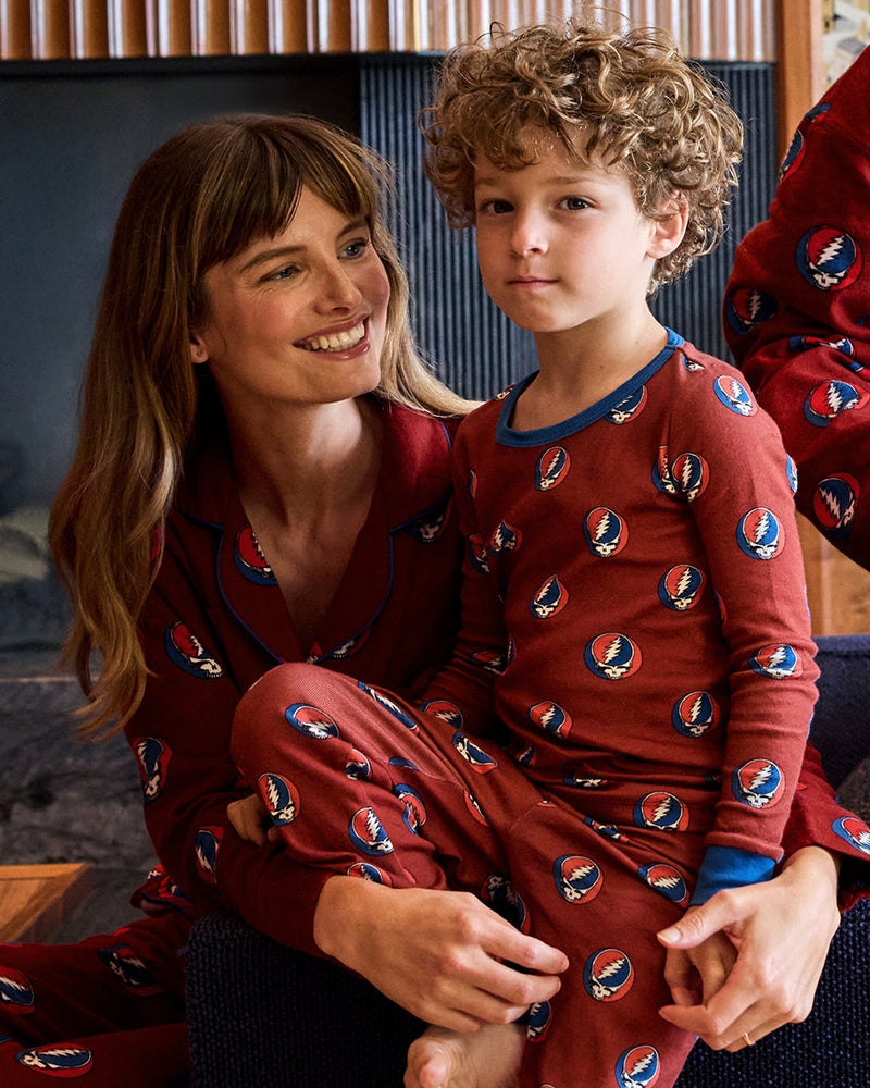 Adult and child in matching red patterned pajamas seated indoors