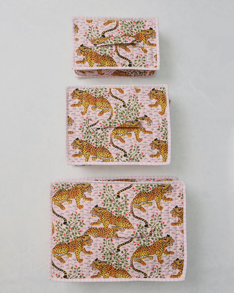 Three pink packing cubes with a leopard-and-leaf print arranged separately on a light background.