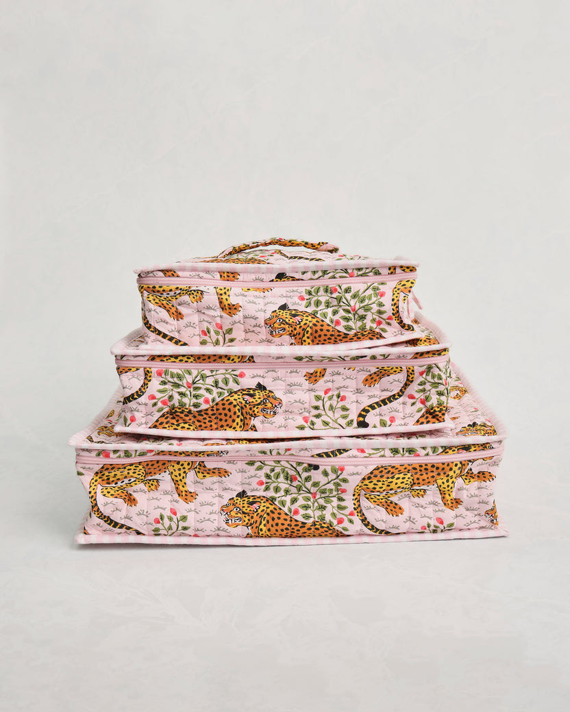 Three pink leopard-and-leaf print packing cubes stacked by size.
