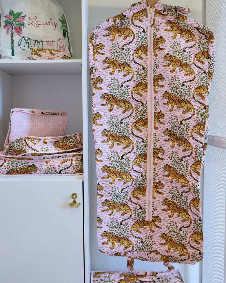 Bagheera blush garment bag hanging in a closet, shown from the front with its zipper and leopard-and-botanical print.