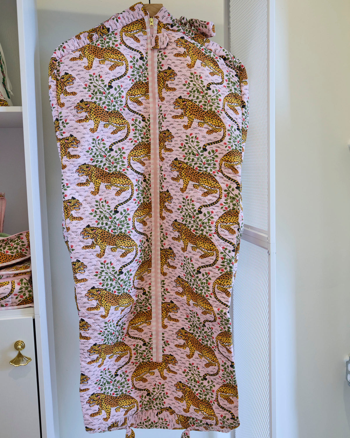 Close front view of the Bagheera blush garment bag with a zipper and leopard-and-botanical print.