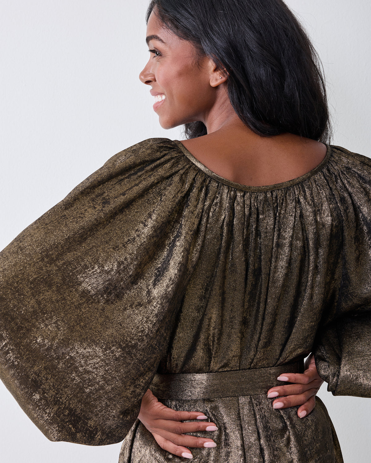 Back view of the gold Glitzy Lamé Felicity dress showing its gathered neckline and sleeves.